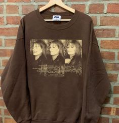 a brown sweatshirt with an image of three women on it