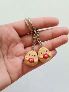 a hand holding two small keychains that have faces on them, one has a red nose and the other has a mouth