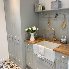 a kitchen with gray cabinets and white flowers in a vase on the sink counter top