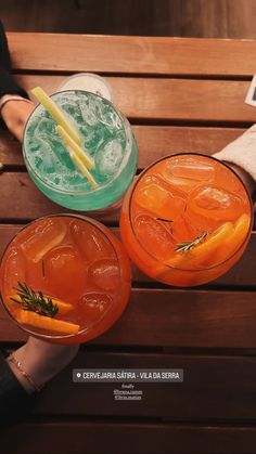 two people sitting on a bench holding drinks