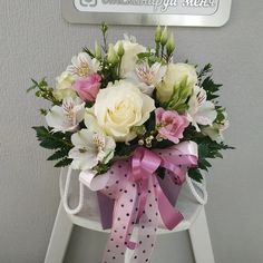 a bouquet of white and pink flowers sitting on top of a stepladder with polka dot ribbon