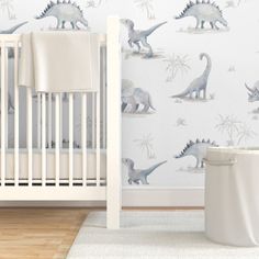 a baby's room with dinosaur wallpaper and a crib in the foreground