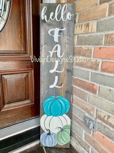 a wooden sign with pumpkins painted on it in front of a brick wall and door