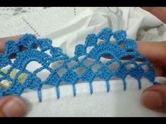 someone is crocheting an intricate piece of fabric with blue yarn on it, and they are holding something in their hands