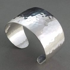 A 1.5 inch wide solid sterling silver cuff with silky smooth edges that tapers off to rounded ends. Given an elegant dome and a bright polish, the hammered facets on this cuff have a watery effect and can reflect light to your surroundings. Eye catching when worn on a night out. Particularly dazzling in sunlight, reflections sparkle like glittering points of light dancing on sunlit waves. Hand cut, formed and hammered by me from solid sterling silver sheet. Stamped STERLING inside with my spiral cat logo. Your personal cuff will be made to fit your wrist so will look similar to photo. Last two photos show where on wrist to take a snug measurement. Descriptive information about example cuff in photo: - 38 grams and slightly springy. - Inside length of oval cuff measures 5.6" with a 0.75" op Genuine Turquoise Jewelry, Stamped Bracelet, Hot Jewelry, Silver Bells, Sterling Bracelets, Ball Bracelet, Turquoise Bracelet Cuff, Turquoise Cuff, Bracelet Cuff