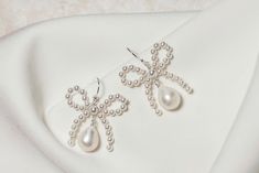 Beautifully simple yet unique pretty bow bridal earrings, handmade using top quality round glass pearls with freshwater teardrop pearls.  The earrings are available in silver, gold, or rose gold plated finish, or you can opt for a more luxurious finish of sterling silver, 14k gold fill, or 14k rose gold fill. The earrings measure approximately 1" in length. Please note that this design incorporates natural freshwater pearls, the beauty of which means each one is unique,  and therefore slight var Elegant Bow Pearl Earrings, White Bow Earrings For Wedding, White Pearl Earrings With Bow For Wedding, Wedding Pearl Drop Earrings With Bow, Elegant Bow Jewelry For Weddings, Elegant Wedding Jewelry With Bow, White Bow Pearl Drop Earrings, Sterling Silver Bow Earrings For Wedding, Elegant Bow Earrings For Wedding