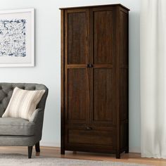 a living room with a gray chair and wooden armoires next to a painting on the wall