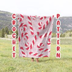 a red and white blanket with the words crocheted on it in front of a field