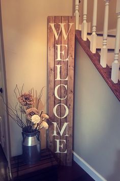 a wooden welcome sign sitting on top of a table next to a potted plant