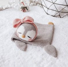 a crocheted stuffed animal laying on top of a white bed covered in snow