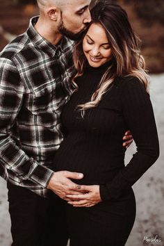 a pregnant couple cuddles and smiles at the camera