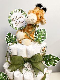 a diaper cake with a stuffed giraffe on top and welcome baby sign