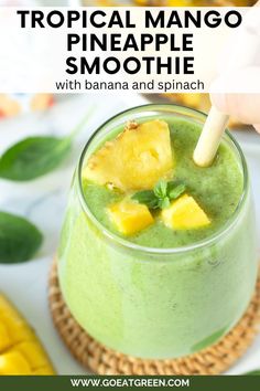 tropical mango pineapple smoothie with banana and spinach in a glass on a plate