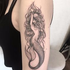 a woman with long hair and a mermaid tail tattoo on her arm