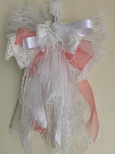 a white dress hanging on the wall with pink and white ribbons tied to it's back