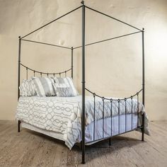 an iron bed frame with blue and white pillows on the top, against a beige wall