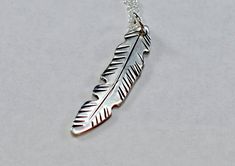 Cut freehand from 18 gauge sterling silver using a fine saw, this dainty feather necklace floats in the breeze with engraved veins and blends organic naturalism with an artistic stylized appearance as a strong intriguing focal point to capture glancing eyes. The feather measures about 1.25 inches long and includes your choice of a 16 inch, 18 inch, or custom length sterling silver link chain that is ever bit as dainty and tasteful as the feather pendant. For a more rustic southwestern style, we Silver Feathered Sterling Silver Necklaces, Silver Sterling Silver Necklaces With Feathers, Moon Goddess Necklace, Silver Feather Necklace, Floating Necklace, Silver Link Chain, Feather Necklace, Feather Pendant, Feather Charms