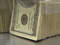 a stack of one hundred dollar bills sitting on top of a metal counter