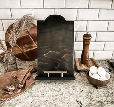 a marble counter top with an easel and some eggs in bowls on the side