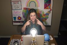 a woman sitting in front of a laptop computer with a light on top of it