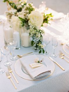 a table set with white and gold place settings