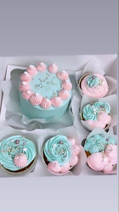 a box filled with lots of cupcakes covered in pink and blue frosting