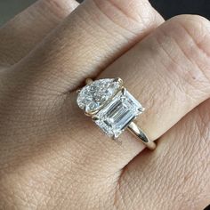 a woman's engagement ring with an emerald cut diamond in the center, on her finger