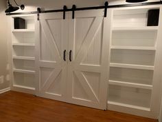 two white barn doors with black hardware on each side and open shelves in the back