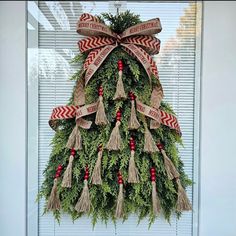 a christmas tree made out of wreaths and burlocks is hanging in front of a window