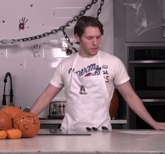 a man standing in front of a counter with two pumpkins on it