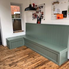 a green bench sitting on top of a wooden floor next to a wall mounted clock