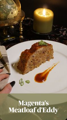 a white plate topped with meatloaf next to a candle