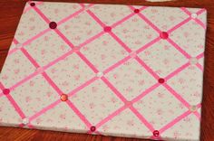 a close up of a piece of cloth on a wooden table with pink and white squares