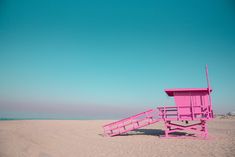 a pink lifeguard tower sitting on top of a sandy beach