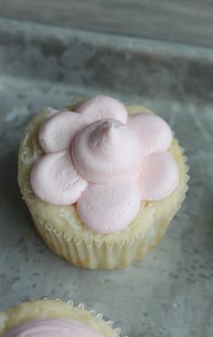 two cupcakes with pink frosting sitting on top of a baking sheet next to each other