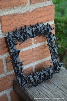 a frame made out of small black objects on a brick wall next to a wooden bench