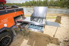 an orange and black camper trailer cooking on the beach