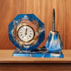 a blue marble clock and pen holder on a wooden shelf