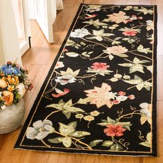 a black rug with flowers on it in the middle of a wooden flooring area