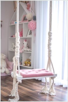 a white swing bed with rope hanging from it's sides in a child's room