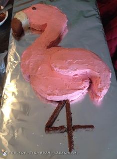 a cake shaped like a pink flamingo sitting on top of a piece of tin foil