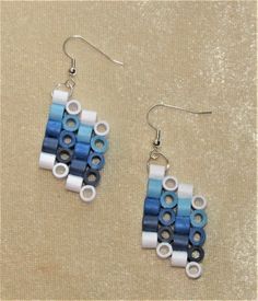 a pair of earrings made out of blue and white legos sitting on top of a table