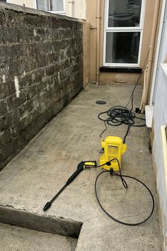 a yellow and black blow dryer sitting on the ground next to a brick wall