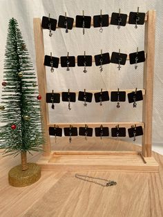 a christmas tree is next to a wooden display rack with earrings on it and a chain hanging from the top