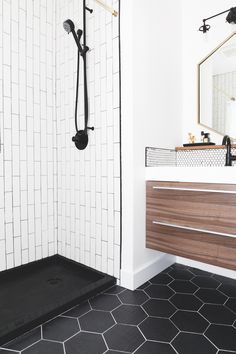 a bathroom with black and white tile flooring, shower head, and vanity sink