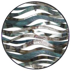 a circular glass window with wavy blue and silver designs on it's side, hanging from a chain