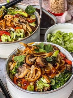 two bowls filled with stir fry vegetables on top of a table