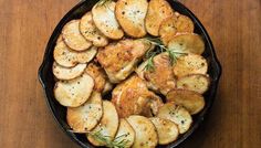 a cast iron skillet filled with seasoned potatoes and garnished with fresh rosemary