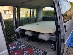 the interior of a van with an open door and wooden table in the back seat