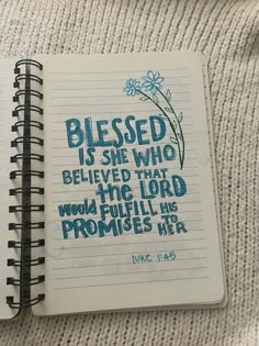 a notepad with a bible verse written in blue ink on top of a white blanket